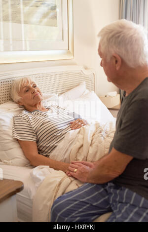 Senior uomo consolante di sua moglie malata nel letto Foto Stock