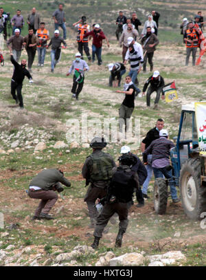 Madama, West Bank. 30 Mar, 2017. Una dimostrazione per commemorare il giorno di terra in Cisgiordania villaggio di Madama, nel sud di Nablus, è diventata violenta come i dimostranti palestinesi si sono scontrati con le forze di sicurezza israeliane. Soldati israeliani sparato gas lacrimogeni e pallottole di gomma a dimostranti palestinesi, che a loro volta sono state gettando le rocce in loro. La protesta si è infiltrata da mascherare i coloni israeliani. Secondo la Mezzaluna Rossa Palestinese 45 palestinesi sono stati feriti sulla scena, mentre senza lesioni dei soldati israeliani sono stati segnalati. Credito: ZUMA Press, Inc./Alamy Live News Foto Stock