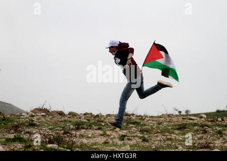 Madama, West Bank. 30 Mar, 2017. Una dimostrazione per commemorare il giorno di terra in Cisgiordania villaggio di Madama, nel sud di Nablus, è diventata violenta come i dimostranti palestinesi si sono scontrati con le forze di sicurezza israeliane. Soldati israeliani sparato gas lacrimogeni e pallottole di gomma a dimostranti palestinesi, che a loro volta sono state gettando le rocce in loro. La protesta si è infiltrata da mascherare i coloni israeliani. Secondo la Mezzaluna Rossa Palestinese 45 palestinesi sono stati feriti sulla scena, mentre senza lesioni dei soldati israeliani sono stati segnalati. Credito: ZUMA Press, Inc./Alamy Live News Foto Stock