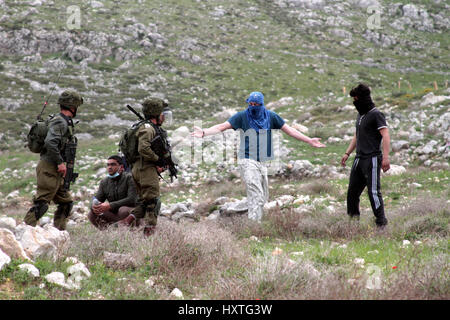 Madama, West Bank. 30 Mar, 2017. Una dimostrazione per commemorare il giorno di terra in Cisgiordania villaggio di Madama, nel sud di Nablus, è diventata violenta come i dimostranti palestinesi si sono scontrati con le forze di sicurezza israeliane. Soldati israeliani sparato gas lacrimogeni e pallottole di gomma a dimostranti palestinesi, che a loro volta sono state gettando le rocce in loro. La protesta si è infiltrata da mascherare i coloni israeliani. Secondo la Mezzaluna Rossa Palestinese 45 palestinesi sono stati feriti sulla scena, mentre senza lesioni dei soldati israeliani sono stati segnalati. Credito: ZUMA Press, Inc./Alamy Live News Foto Stock