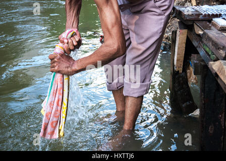 Un asciugamano per il lavaggio dell'uomo nel fiume Ciliwung, Giacarta, Indonesia. Foto Stock