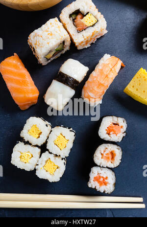 Nero ardesia vassoio assortiti di sushi e panini. Foto Stock