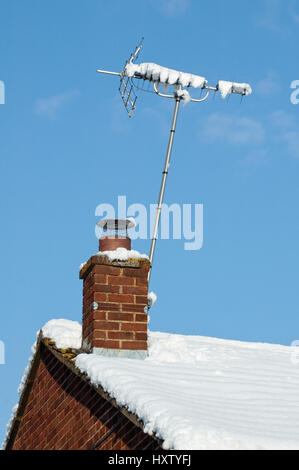 Coperta di neve antenna televisiva sul tetto invernale Foto Stock