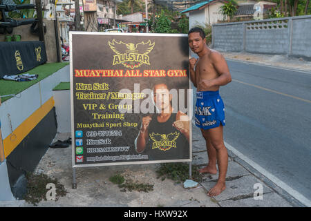 Kru Sak, il Muay Thai o Thai boxer, pone accanto a un cartellone presenta la sua palestra a Phuket, Tailandia. 09-Mar-2017 Foto Stock