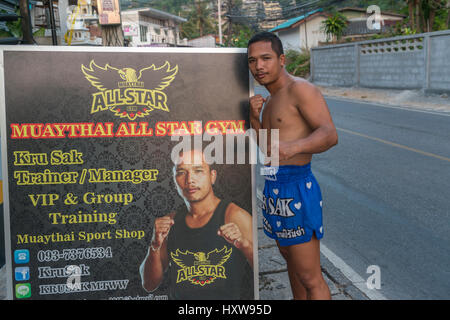 Kru Sak, il Muay Thai o Thai boxer, pone accanto a un cartellone presenta la sua palestra a Phuket, Tailandia. 09-Mar-2017 Foto Stock