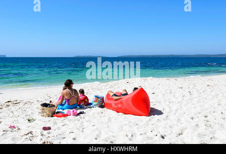 La famiglia in un momento di relax a Hyams Beach, un popolare spettacolare tratto di Jervis Bay con sabbia bianca e finissima, Nuovo Galles del Sud, NSW, Australia Foto Stock