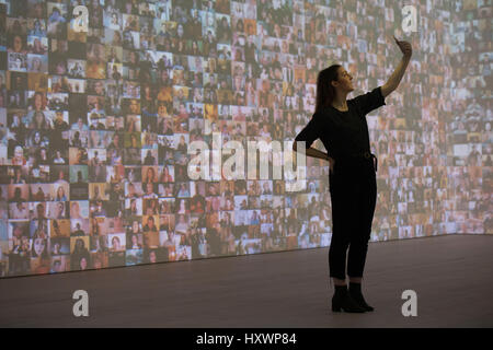 Un visitatore assume un selfie davanti a una grande scala visiva audio installazione dal titolo "Hello World!", 2008, da Christopher Baker durante una anteprima di stampa al Selfie a Self-Expression mostra alla Saatchi Gallery di Londra, che analizza la storia del selfie dal ritratto artisti attraverso al giorno moderno selfies. Foto Stock