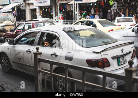 Un ragazzo sta guardando fuori dalla finestra di un taxi in Amman, Giordania. Foto Stock