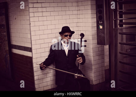 Un musicista di strada è la riproduzione del "Erhu" in mezzo alla stazione della metropolitana di New York, Stati Uniti d'America. Foto Stock