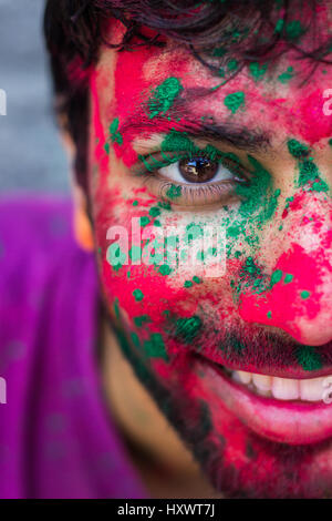 Metà faccia il ritratto di una giovane ragazzo coperto con colori durante il festival di colori, Holi in India. Foto Stock