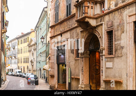 Trento, Italia - 21 Marzo 2017: Case con svariati tipi di facciate in un vicolo del centro storico. Le macchine vengono parcheggiate parallelo. Foto Stock