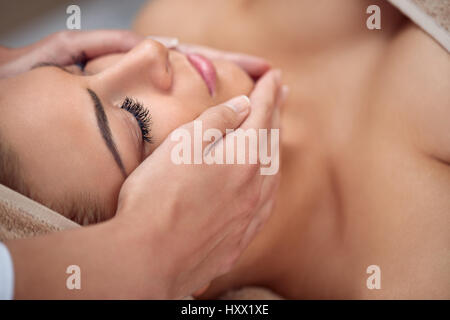 Close-up di una giovane donna di ottenere il trattamento termale al salone di bellezza. spa il massaggio del viso. Bellezza viso trattamento. spa salone. Foto Stock