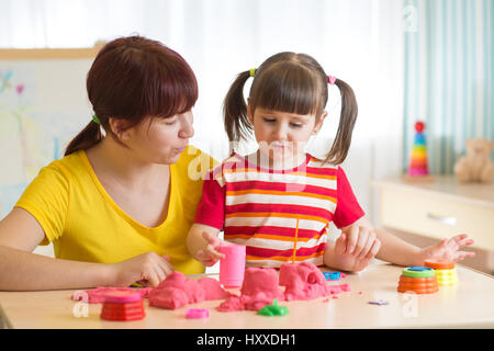 La ragazza del bambino e la madre gioca con la costruzione di sabbia giocattolo a casa Foto Stock