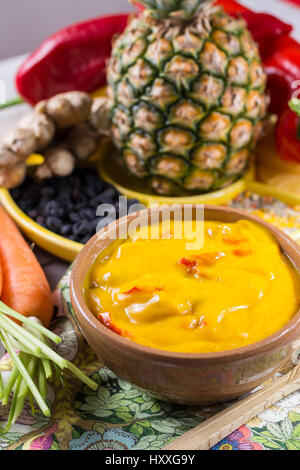 Ciotola di verdura salsa al curry e gli ingredienti che entrano nella rendendo - paprica, peperoncino, carote, ananas, gember. Ampiamente utilizzato in cucina indiana. Foto Stock