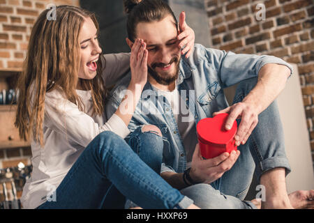 Eccitato giovane uomo riceve presente dalla sua bella ragazza Foto Stock