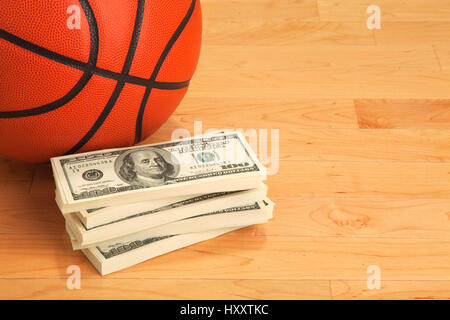 Il basket e la pila di banconote da cento dollari sulla corte di legno piano Foto Stock