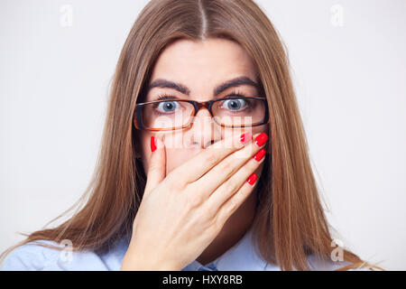 Io non ci credo! Giovane donna di affari tenendo la mano vicino alla bocca isolati su sfondo grigio. Foto Stock