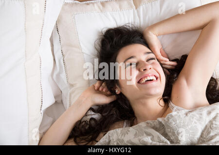 Giovane donna di ridere e di stretching nel letto dopo un buon riposo Foto Stock