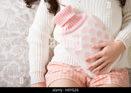 Giovane donna con hot-bottiglia d'acqua sulla pancia Foto Stock