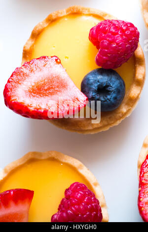 Poco crostate di pasticceria farciti di crema e frutti di bosco freschi Foto Stock