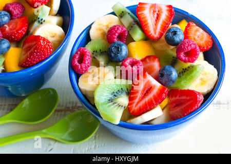 Varia e colorata insalata di frutta in blu bocce su tavola in legno rustico Foto Stock