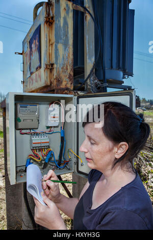 Donna ingegnere elettricista ispezione contatore elettrico attrezzature di distribuzione nella scatola dei fusibili, elettricità switchgear trasformatore di potenza sottostazione, superarsi Foto Stock