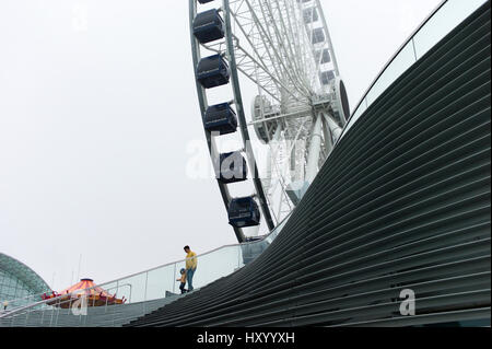 Un uomo e ragazzo a piedi passato la nuova ruota Centennial ruota panoramica Ferris a Navy Pier in Chicago il lunedì, 27 Mar, 2017. Foto Stock