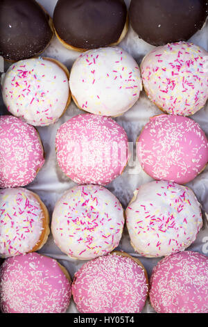 Un assortimento di diverse deliziose ciambelle in una scatola, primo piano Foto Stock