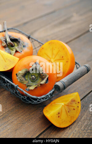 Ripe persimmons dolce nel cestello sul tavolo di legno closeup Foto Stock