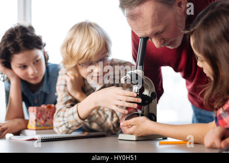 Basta guardare a questo. Entusiastico lavoro duro i giovani scienziati di dimostrare alcune reazioni di batteri utilizzando un microscopio e attesa per i loro insegnanti Foto Stock