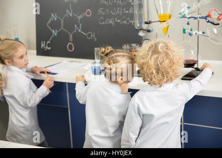 I bambini che indossano camici da laboratorio e studiare nel laboratorio di scienze Foto Stock