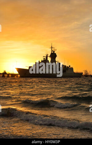 Alba sagome di luce la Royal Australian Navy fregata HMAS Perth, a munizioni Wharf, Isola Giardino base navale, Western Australia. Foto Stock