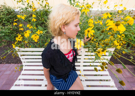 Primo piano della giovane donna maleodoranti tall giallo girasole fiori a margherita sul banco di lavoro Foto Stock