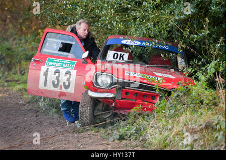 Aldershot, Regno Unito - 3 Novembre 2012: Sicurezza equipaggio contribuendo a trainare un scatafascio Ford Escort fuori del undergrow sul padiglione del palco di MSA Tempest Rall Foto Stock