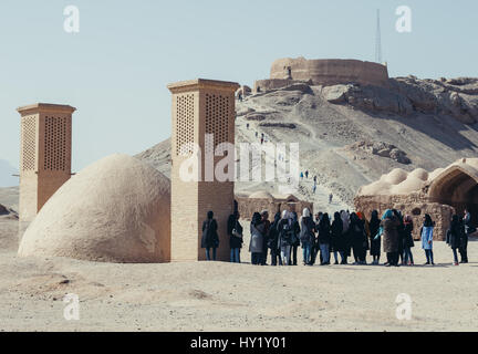 Gruppo di turisti iraniani accanto al serbatoio di acqua con vento catturatori sulla zona di Torre zoroastriana di silenzio (visto sullo sfondo) in Yazd, Iran Foto Stock