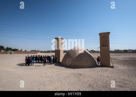 Gruppo di turisti iraniani accanto al serbatoio di acqua con vento catturatori sulla zona di Torre zoroastriana di silenzio (visto su bacground) in Yazd, Iran Foto Stock