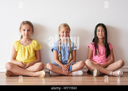 Le tre ragazze seduta con le gambe incrociate Foto Stock