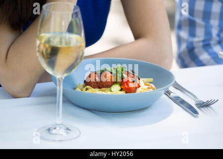 Immagine ritagliata della coppia con cibo e wineglass sul tavolo al ristorante Foto Stock