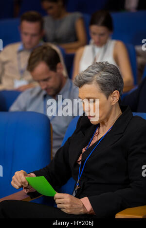 Business executive guardando al green card presso il centro conferenze Foto Stock