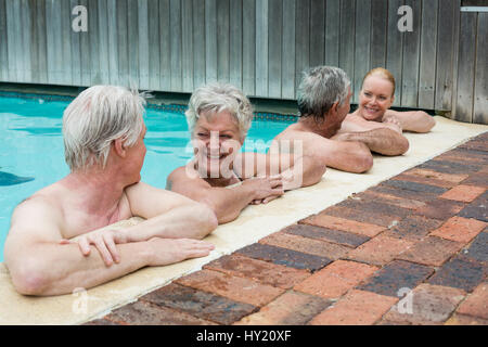 Fila di nuotatori appoggiata sul bordo della piscina Foto Stock