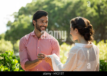 Uomo felice mettendo anello di fidanzamento sulla donna in posizione di parcheggio Foto Stock