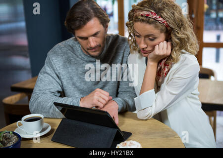 Coppia giovane con tavoletta digitale a tavola in coffee shop Foto Stock