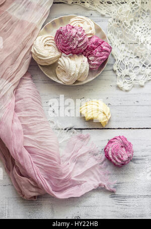 Zephyr (Russo marshmallow) sulla luce tavolo in legno con panno di colore rosa e bianco centrino a crochet. Vista superiore Foto Stock