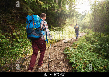 Due escursionisti a piedi lungo un sentiero nel cuore della foresta Foto Stock