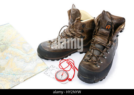 Un paio di scarpe da trekking Alberg in pelle tradizionale usata, la mappa a piedi e la bussola di navigazione sul bianco. Inghilterra Regno Unito Gran Bretagna Foto Stock