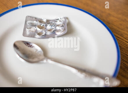 Set di pillole in una plastica e confezione giacente sul vassoio bianco con bordo blu Foto Stock