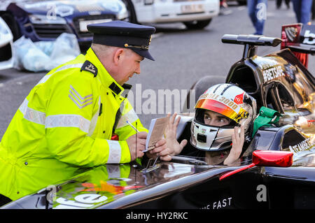 Dublino, Irlanda: 30 APR 2016 - un driver viene arrestato da una polizia di Garda sergente prima della partenza della Gumball Rally 3000 2016, da Dublino a Budapest e rilasciato con un biglietto di accelerazione (poste shot). Foto Stock