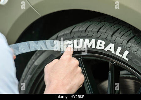 Dublino, Irlanda: 30 APR 2016 - Una vettura si applica detailler bianco 'Gumball' lettering in gomma per il pneumatico di una Rolls Royce prima della partenza della Gumball Rally 3000 2016, da Dublino a Budapest. Foto Stock