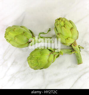 Carciofi su marmo bianco texture con copyspace Foto Stock