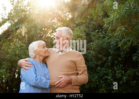 Contenuto coppia senior in piedi in ogni altra di braccia al di fuori Foto Stock